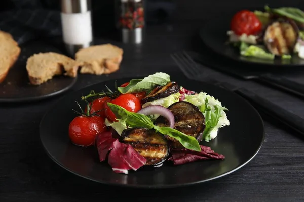 Kızarmış patlıcan ve siyah ahşap masada servis edilen fesleğenli lezzetli salata.