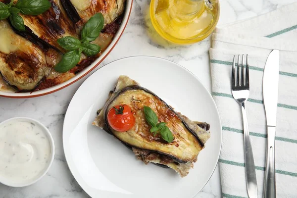 Delicious eggplant lasagna served on white marble table, flat lay