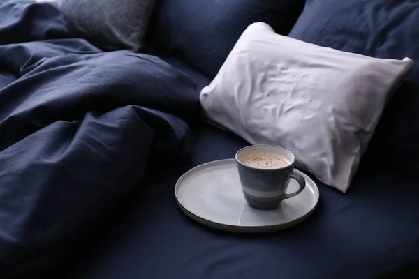 Cup of coffee on bed with stylish silky linens