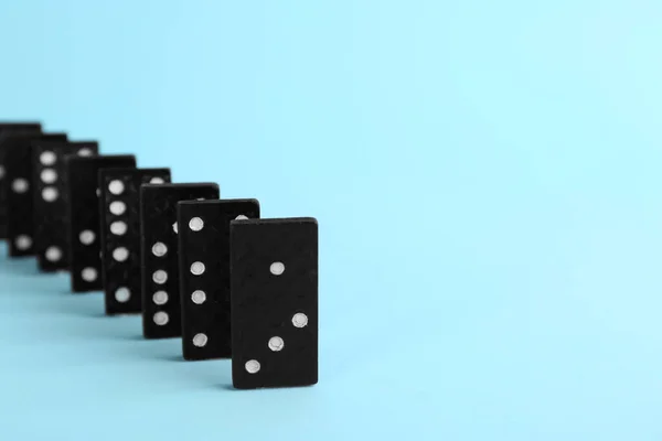Row of black domino tiles on light blue background. Space for text