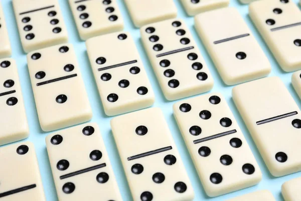 Açık mavi arkaplanda klasik domino taşları kümesi, yakın plan
