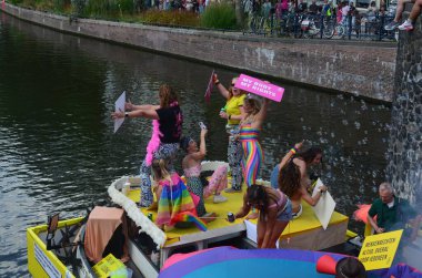AMSTERDAM, NETHERLANDS - AUGUST 06, 2022: Many people in boat at LGBT pride parade on river