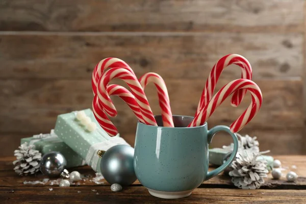 Many sweet candy canes, gift boxes  and Christmas decor on wooden table
