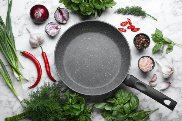 Flat lay composition with frying pan and fresh products on white marble table