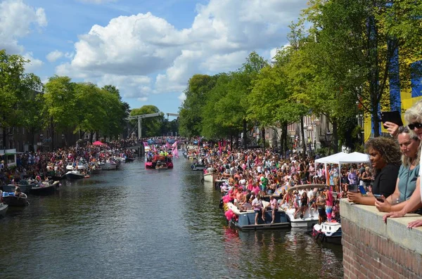 AMSTERDAM, NETHERLANDS - AUGUST 06, 2022: Many people in boats at LGBT pride parade on river