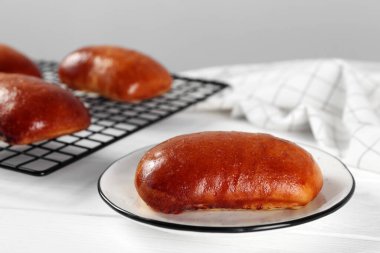 Delicious baked pirozhki on white wooden table, closeup