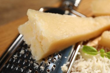 Grated parmesan cheese with basil near grater, closeup