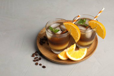 Tasty refreshing drink with coffee and orange juice on grey table
