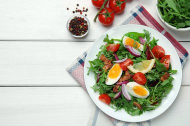 Delicious salad with boiled eggs, vegetables and bacon served on white wooden table, flat lay. Space for text