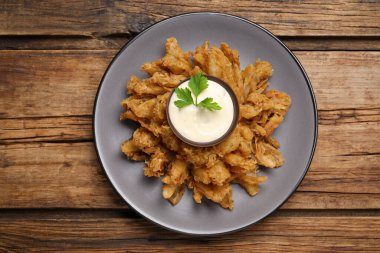 Ahşap masada servis edilen soslu kızarmış soğan.