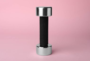 One metal dumbbell on light pink background