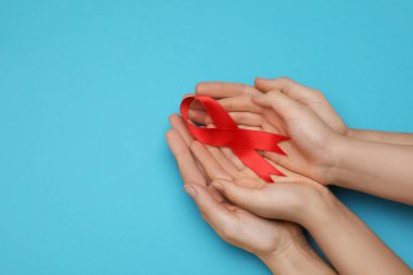 Mavi arka planda kırmızı kurdele tutan kadın ve kız. Üstü açık, mesaj için yeri var. AIDS Hastalığı Farkındalığı