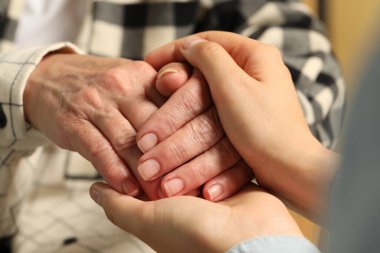 Young and elderly women holding hands, closeup