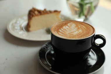 Cup of fresh coffee and dessert on white table, closeup