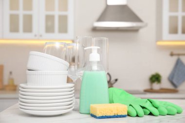 Set of clean dishes and cleaning product on table in stylish kitchen