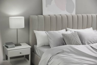 Işık odasında yumuşak ipek çarşaflı rahat bir yatak.