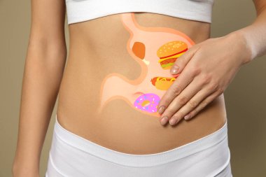 Woman with image of stomach full of junk food drawn on her belly against beige background, closeup. Unhealthy eating habits