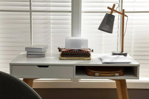 Comfortable writer\'s workplace with typewriter on desk in front of window
