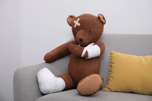 Toy Bear Bandages Sitting Sofa Light Wall —  Fotos de Stock