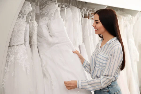 Genç bir kadın gelinliği kuaförde seçiyor.