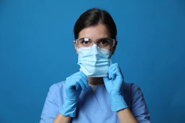 Врач Защитной Маске Медицинских Перчатках Очках Синем Фоне — стоковое фото