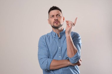 Gri arka planda günlük kıyafetli duygusal bir adam.