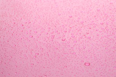 Pembe arkaplanda su damlaları, yakın çekim görüntüsü