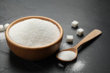 Granulated sugar in bowl on dark table