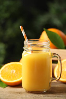 Mason jar of orange juice and fresh fruits on wooden table