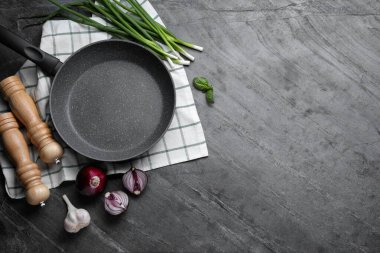 Flat lay composition with frying pan and fresh products on grey table, space for text