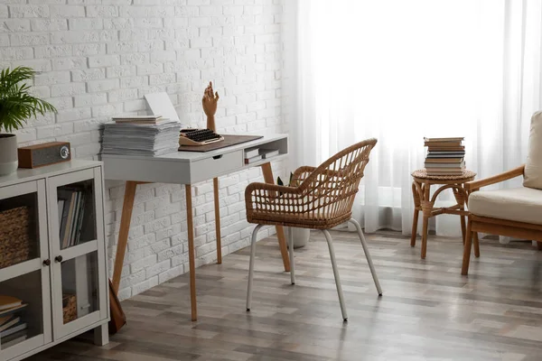 Comfortable writer's workplace interior with typewriter on desk near white brick wall