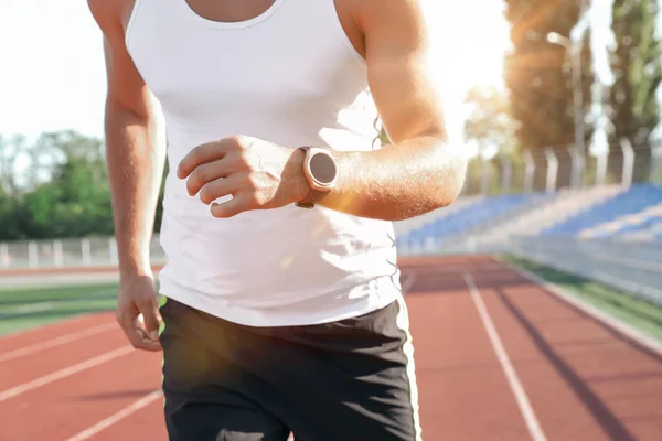 Man with fitness tracker running at stadium, closeup