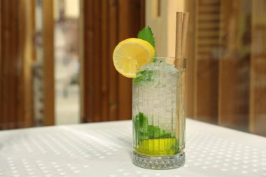 Glass of refreshing citrus drink on white table indoors