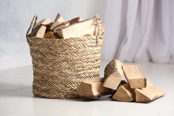 Beyaz zeminde kesilen odunlarla dolu bir sepet.