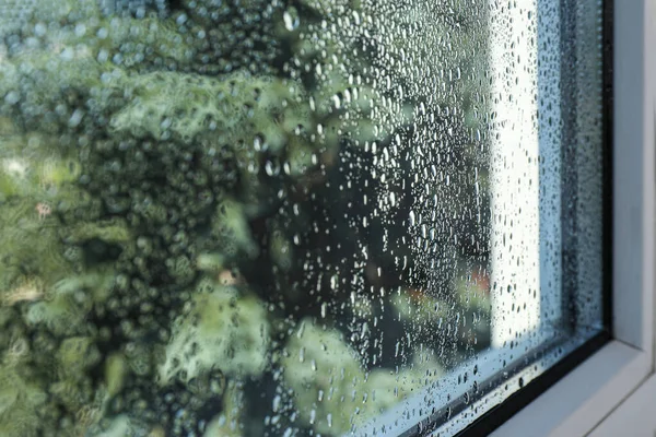 Window glass with drops of condensate indoors, closeup