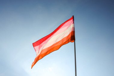 Bright lesbian flag fluttering against blue sky