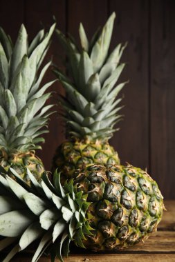 Fresh ripe juicy pineapples on wooden table, closeup