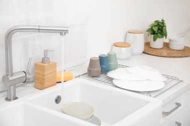 Drying rack with clean dishes near sink in stylish kitchen