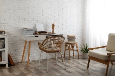 Comfortable writer's workplace interior with typewriter on desk near white brick wall
