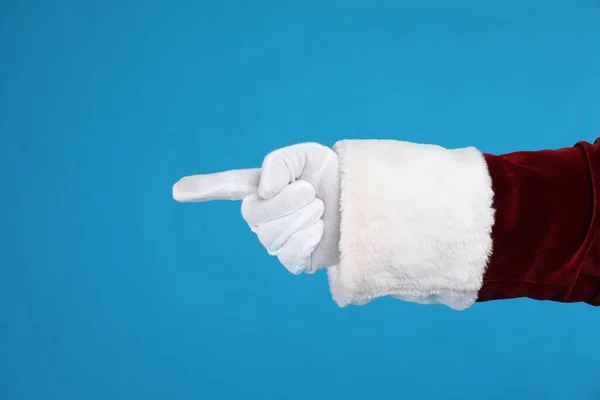サンタクロースは青い背景に何かを指して 手の近くに — ストック写真