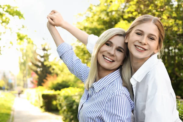 Mutlu anne kızıyla birlikte güneşli bir günde parkta vakit geçiriyor.