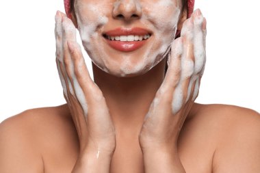 Beautiful woman applying facial cleansing foam on white background, closeup
