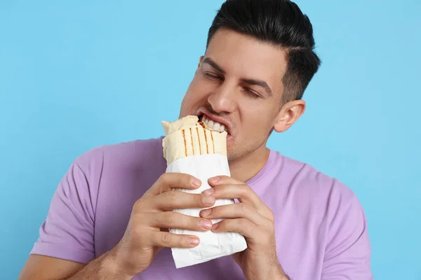 Człowiek Jedzący Pyszne Shawarma Turkusowym Tle — Zdjęcie stockowe