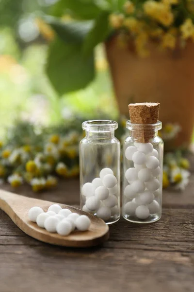 Bottles of homeopathic remedy and flowers on wooden table