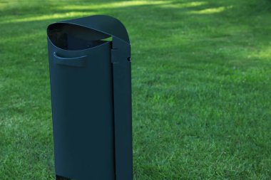 Trash bin on green grass outdoors. Space for text