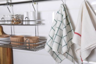 Different kitchen towels hanging on hook rod and shelves with bowls indoors
