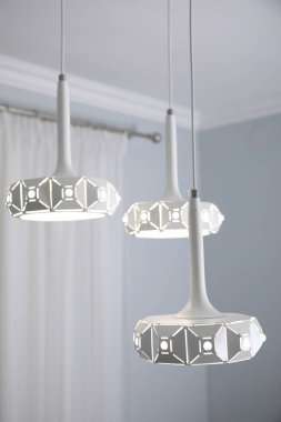 Stylish pendant lamp on white ceiling indoors