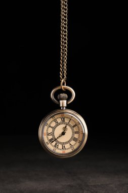Stylish pendulum above table on black background. Hypnotherapy session