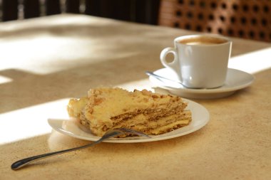 Piece of delicious cake and coffee on beige table, closeup