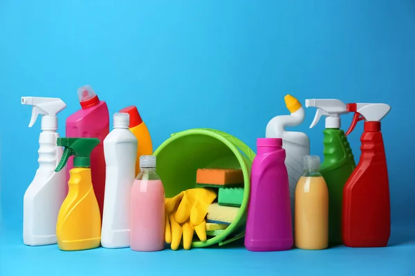 Green bucket, cleaning supplies and tools on light blue background